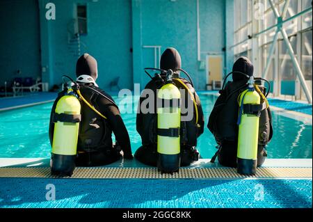 Instructeur et deux plongeurs en costume, vue arrière Banque D'Images