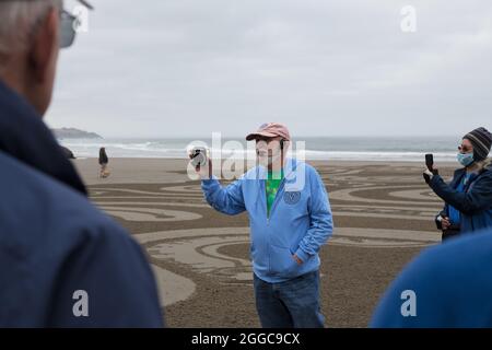 Denny Dyke, artiste du sable, parle à la foule à l'ouverture de son labyrinthe de sable, à Bandon, Oregon, États-Unis. Banque D'Images