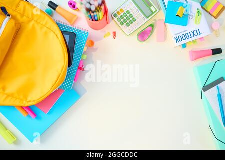 Retour à l'école. Vue supérieure d'un bureau blanc avec des classeurs, des articles de papeterie, des manuels et un sac à dos dans la chambre d'enfant de l'école par beau temps. Banque D'Images