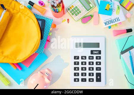 Retour à l'école. Vue supérieure d'un bureau blanc avec des classeurs, des articles de papeterie, des manuels, une calculatrice et un sac à dos dans la chambre d'enfant de l'école par beau temps. Banque D'Images