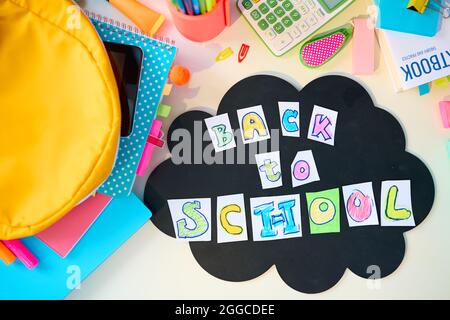 Retour à l'école. Vue supérieure du bureau blanc avec classeurs, papeterie, manuel, nuage, inscription rentrée scolaire et sac à dos dans la chambre d'enfant de l'école Banque D'Images