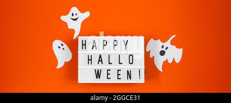 Joyeux Halloween. Des fantômes de papier amusants pour les vacances sur fond orange. Format de bannière. Banque D'Images