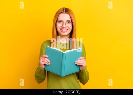 Photo portrait rouge cheveux femme en lunettes lecture livre isolé couleur jaune vif arrière-plan Banque D'Images