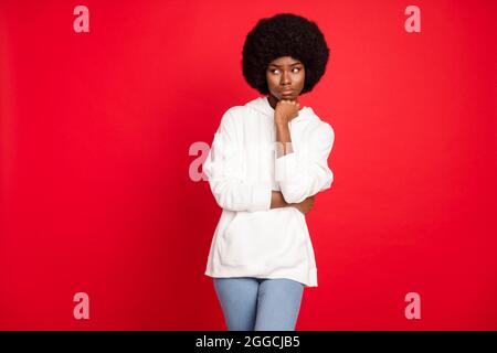 Photo de think brunette cheveux jeune femme poing visage look vide espace porter blanc hoodie isolé sur fond rouge couleur Banque D'Images