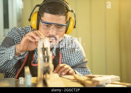 Portrait menuisier homme heureux beau travail à la recherche et le choix du bois dans l'atelier.Carpenter travaillant avec l'équipement sur la table en bois en voiture Banque D'Images