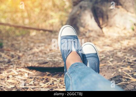 Chaussures de randonnée jeune femme voyageur s'assoit sur le parc d'été.concentrez-vous sur les chaussures de basket bleues et les jeans sur le sentier. Activité active vacances sur la montagne de randonnée Banque D'Images