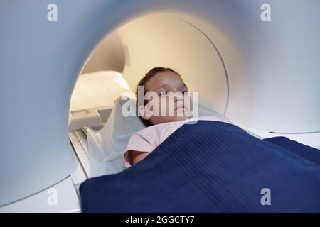 Enfant mignon recouvert d'une serviette bleue qui va subir un examen médical dans un appareil d'irm Banque D'Images