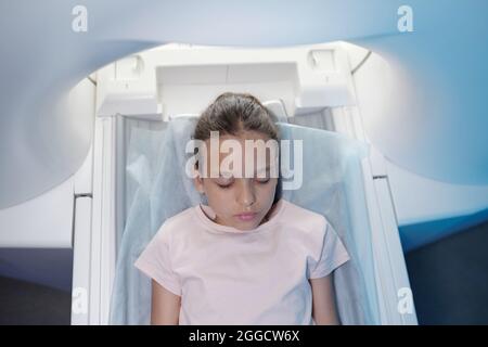 Vue de la petite fille gardant les yeux fermés avant de subir un examen CT dans les cliniques modernes Banque D'Images