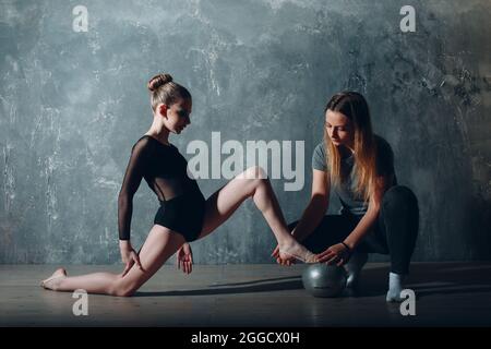 Jeune fille gymnaste professionnelle avec entraîneur femme danse gymnastique rythmique au studio. Banque D'Images