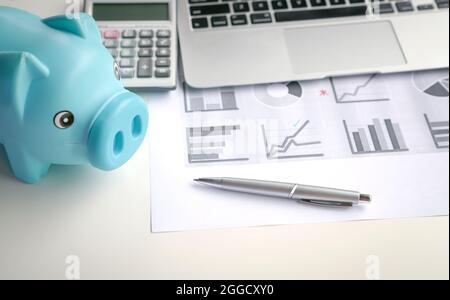 Banque de porc, graphiques et graphiques, calculatrice, stylo et ordinateur portable sur table, concept d'investissement. Banque D'Images