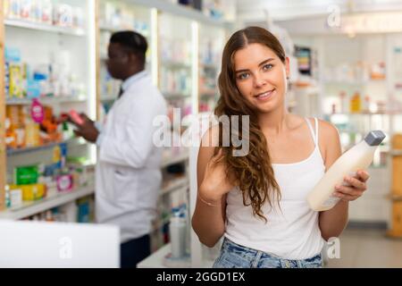 Adolescente choisissant des produits de soins capillaires en pharmacie Banque D'Images