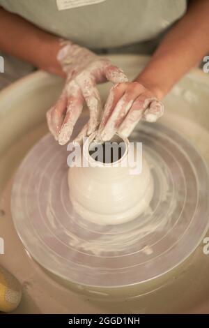 De ci-dessus crop anonyme femme artisan façonnant vase d'argile humide tout en travaillant à la roue de poterie en studio d'art Banque D'Images