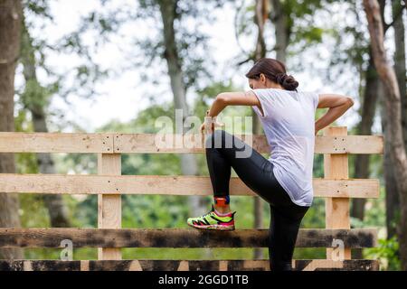 Jeune sportswoman escalade mur de bois sur son parcours de course d'obstacles Banque D'Images