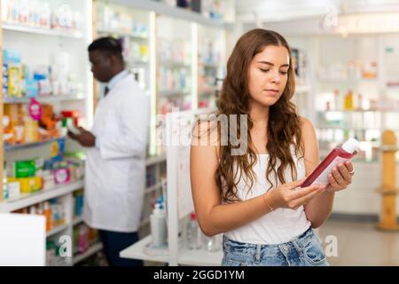 Adolescente choisissant des produits de soins capillaires en pharmacie Banque D'Images