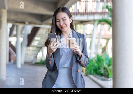 Concept de femme de travail une jeune femme gestionnaire tient une tasse de café et communique avec l'collègue par l'intermédiaire de l'appel vidéo. Banque D'Images