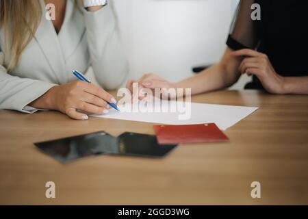 Femme qui choisit et achète une voiture dans la salle d'exposition. Le vendeur de voitures l'aide à prendre la bonne décision. Documents de signalisation féminine Banque D'Images