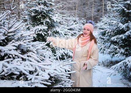 Une femme choisit un arbre de Noël dans la pépinière en nature d'hiver à la Saint-Sylvestre Banque D'Images