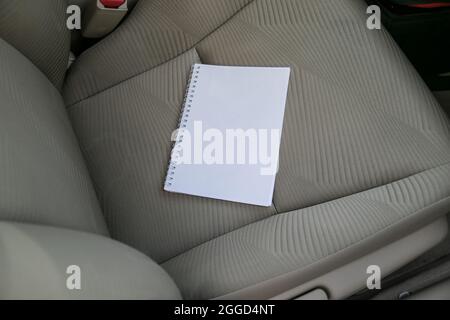 Ouvrez le carnet avec des pages vierges blanches vierges transparentes sur le siège de voiture Banque D'Images