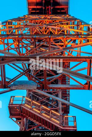 Tour de mine située dans le musée silésien de Katowice, Silésie, Pologne vu d'en dessous. Bâtiment industriel illuminé de manière spectaculaire sur le s. Banque D'Images