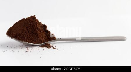 Cuillère avec café moulu sur fond blanc Banque D'Images