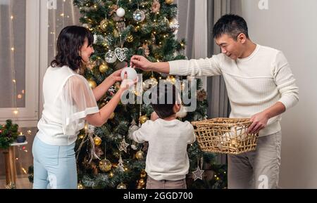 Une famille heureuse décorant l'arbre de noël ensemble Banque D'Images