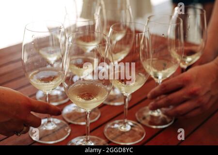 Verres avec différents types de vin et mains humaines tenant des verres à vin en arrière-plan. Dégustation de vin Banque D'Images