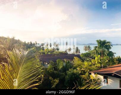 Vue aérienne des toits rouges des maisons, des palmiers et de l'océan. Paysage tropical sur l'île. Nuages et ciel bleu sur l'île. Concept de voyage et de vacances Banque D'Images