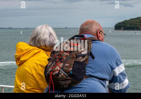 un couple d'âge moyen qui regarde la mer, un couple plus âgé sur la côte, un couple à la retraite qui se penche sur les chemins de fer qui regardent la vue sur la mer, l'ensemble. Banque D'Images