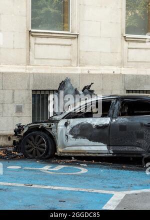 Voiture détruite brûlée sur une aire de stationnement pour handicapés dans le parking Banque D'Images