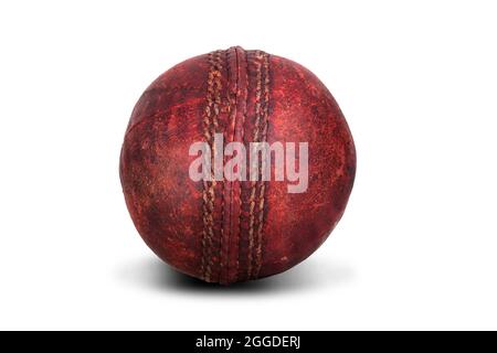 Vieux cuir de balle de cricket rouge avec coutures isolées sur fond blanc. Équipement de sport usé Banque D'Images