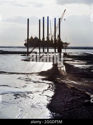 Une vue sur le 'Jay Robertson', une grande barge, qui travaille dans la rivière Severn pendant la construction du second Severn Crossing. Le 'Jay Robertson' était une grande barge de levage travaillant dans la rivière Severn près de la plage Severn, pendant la construction du second Severn Crossing. Il a été utilisé pour forer des pieux à travers le lit de mer pour deux pières de soutien de viaduc près du tunnel ferroviaire Severn. Banque D'Images