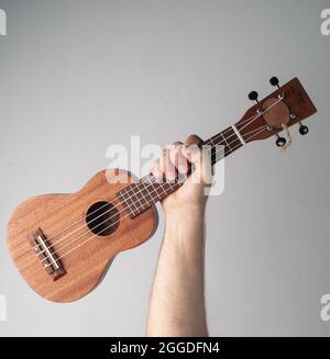 main avec un ukulele sur fond blanc, jour du travail Banque D'Images