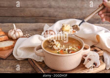 Femme mangeant de la soupe savoureuse d'orge de bœuf sur table Banque D'Images