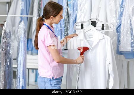 Femme travaillant à la vapeur des vêtements dans les nettoyeurs à sec modernes Banque D'Images