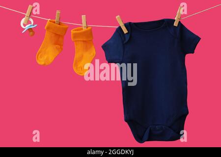 Vêtements et sucette pour bébé suspendus sur corde sur fond de couleur Banque D'Images