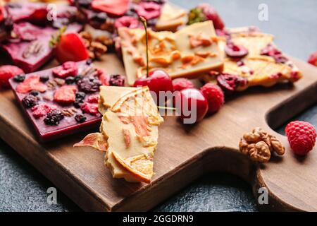 Barres chocolatées faites à la main avec fruits et noix sur fond sombre Banque D'Images