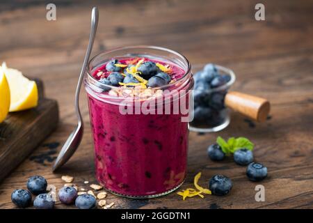 Smoothie aux myrtilles épaisses dans un pot en verre sur une table en bois. Nourriture végétalienne Banque D'Images