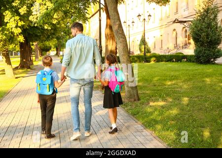 De jolis petits enfants vont à l'école avec leur père Banque D'Images