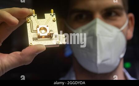 31 août 2021, Basse-Saxe, Brunswick: Le physicien Markus Duwe présente un processeur quantique sur un prototype d'ordinateur quantique au Physikalisch-Technische Bundesanstalt PTB. La Basse-Saxe veut faire avancer la technologie quantique avec des sommes de milliards. Plus de 1.5 milliards d'euros seront consacrés à la nouvelle technologie d'ici 2030, a annoncé l'association de recherche de Basse-Saxe 'Quantum Valley Basse-Saxe'. D'ici 2025, le premier ordinateur quantique de l'État doit être mis en service. Photo: Julian Stratenschulte/dpa Banque D'Images