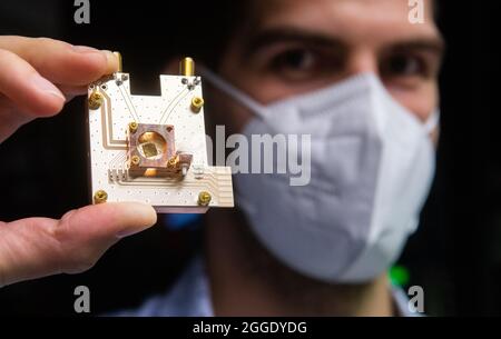 31 août 2021, Basse-Saxe, Brunswick: Le physicien Markus Duwe présente un processeur quantique sur un prototype d'ordinateur quantique au Physikalisch-Technische Bundesanstalt PTB. La Basse-Saxe veut faire avancer la technologie quantique avec des sommes de milliards. Plus de 1.5 milliards d'euros seront consacrés à la nouvelle technologie d'ici 2030, a annoncé l'association de recherche de Basse-Saxe 'Quantum Valley Basse-Saxe'. D'ici 2025, le premier ordinateur quantique de l'État doit être mis en service. Photo: Julian Stratenschulte/dpa Banque D'Images