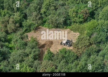 La pelle prépare le sol sur le terrain dans la forêt parmi les arbres pour l'aménagement paysager et l'agriculture, vue de dessus - Moscou, Russie, 24 août 2021 Banque D'Images