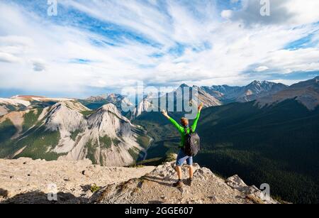 Randonneur étire ses bras dans l'air, paysage de montagne avec la vallée de la rivière et les pics, pics avec des dépôts de soufre orange, Overturn Mountain, panoramique Banque D'Images