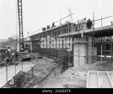 Vue de la construction de l'autoroute Birmingham-Preston (M6), montrant la première des grandes poutres post-tensionnées concrétisées in situ sur le pont 306 (pont Barn Bank Lane). Dans l'album, la légende dactylographiée ci-dessous la photo indique "béton étant placé à la première des grandes poutres post-tendues de 95'-0" de long, 70 tonnes sur le pont 306/ (Barn Bank Lane). Ceux-ci sont coulés sur les butées et les jetées en raison des difficultés de manipulation des poutres de cette taille. Ce faisceau particulier a maintenant été soumis à des contraintes et est auto-soutenu sur toute la plage. » Ce pont routier, qui est situé Banque D'Images