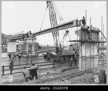 Le premier faisceau sur la chaussée en direction du sud étant levé en position, lors de la construction d'une passerelle dans la zone de service de Newport Pagnell sur l'autoroute de Londres à Yorkshire (M1). Cette image a été cataloguée dans le cadre du projet Breaking New Ground en partenariat avec la John Laing Charitable Trust en 2019-20. Banque D'Images