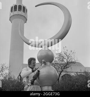 Mosquée centrale de Londres et centre culturel islamique, Park Road, Regent's Park, Cité de Westminster, Autorité du Grand Londres, 15/03/1977. Vue rapprochée d'un homme avec le croissant de finial devant la mosquée centrale de Londres, avant qu'il ne soit soulevé sur le toit bombé de la salle de prière. Le fiel a été fabriqué à partir de béton armé en fibre de verre (GRC) dans le Northamptonshire, et peint dans le sud du pays de Galles pour donner une finition dorée. Banque D'Images