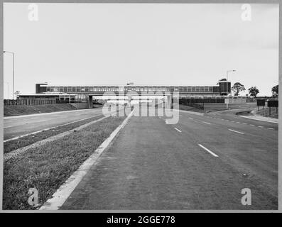 Vue vers le nord en direction de la structure 347A, dans la zone de service Keele de l'autoroute Birmingham-Preston (M6), montrant un panneau d'entrepreneur Laing sur la passerelle couverte au-dessus de l'autoroute. Cette image a été cataloguée dans le cadre du projet Breaking New Ground en partenariat avec la John Laing Charitable Trust en 2019-20. Banque D'Images