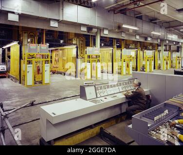 Un homme assis à un poste de contrôle de Ford Motor Company Works, exploitant une rangée de grues Munck. Cette image a été cataloguée dans le cadre du projet Breaking New Ground en partenariat avec la John Laing Charitable Trust en 2019-20. Banque D'Images
