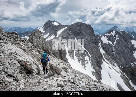 Randonnée sur un chemin sur la roche, chemin de crête avec des restes de neige, panorama de montagne avec pic de lumière, ciel nuageux spectaculaire, Heilbronner Weg, Allgaeu Banque D'Images