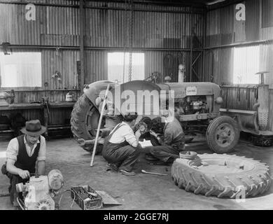 Vue de deux travailleurs de Laing effectuant des travaux d'entretien sur la roue arrière droite d'un tracteur diesel Fordson Major. Cette image a été cataloguée dans le cadre du projet Breaking New Ground en partenariat avec la John Laing Charitable Trust en 2019-20. Banque D'Images