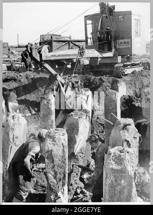 Travaux de base en cours pour l'unité de distillation du brut de la raffinerie de pétrole de Coryton, montrant des hommes qui travaillent sur des fondations de pieux et une machine de rétro-acteur excavant entre des pieux. La légende sous cet album est : « unité de distillation brute - 16 po x 16 po de hauteur et tas de râtelage, brisant le béton entourant le renfort principal avant de brûler au niveau de la coupe. L'acteur de fond excavant entre les piles (fondations de la tour).' La raffinerie de pétrole de Coryton a été ouverte par cérémonie en mai 1954 par sa Majesté la reine Elizabeth, la reine mère. Il a été exploité par Vacuum Oil Company; une unité de Banque D'Images